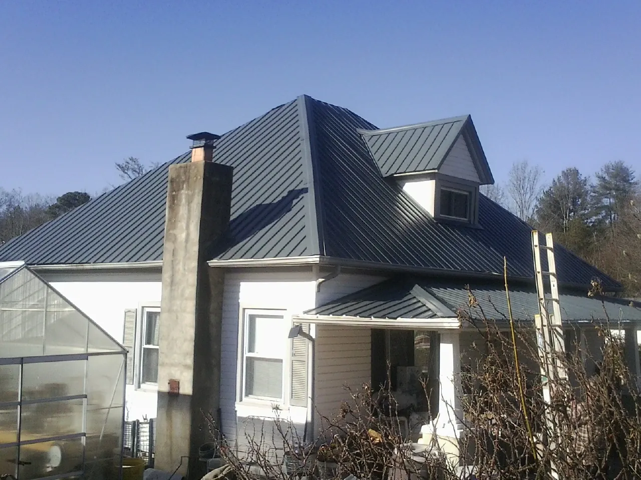 Dark blue standing seam metal roof on a white farmhouse with dormer — Slate & Tile Roof Repair by Roofing Brothers in Cataula