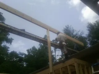 Carpenter setting a ridge beam over a new addition frame — Ice Dam Removal by Roofing Brothers in Cataula