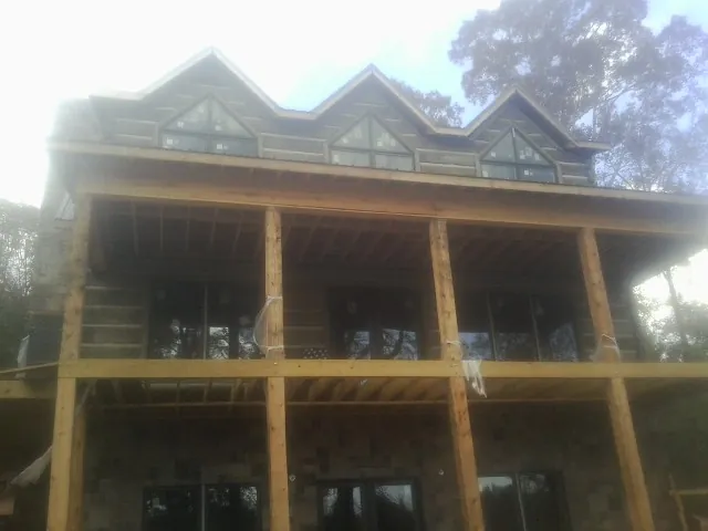 Dormers and porch framing on a large log home under construction — Roof Coating work by our crew in Cataula