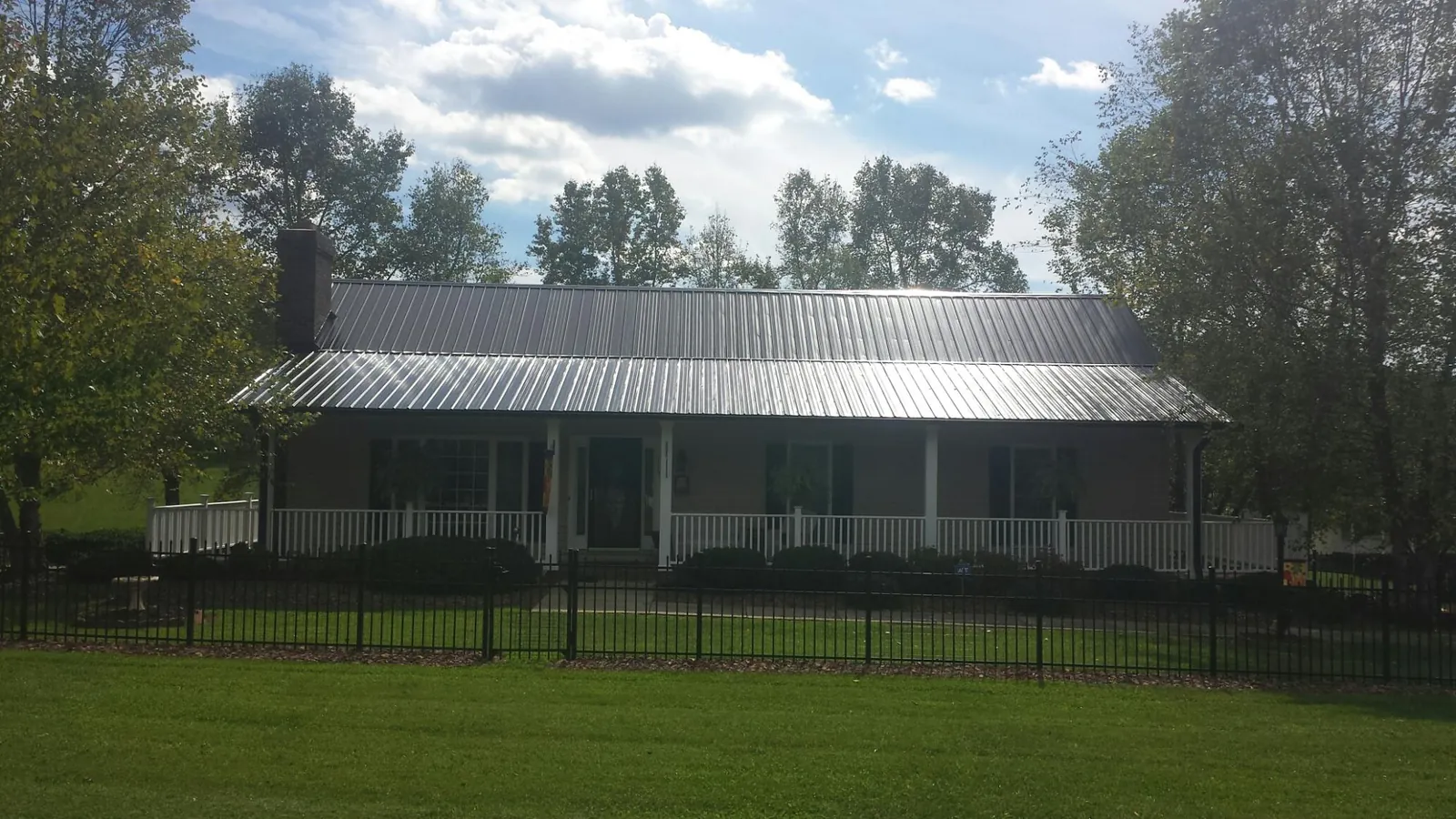 Gray metal roof on a brick ranch with a full width front porch — Gutter Guard Installation work by our crew in Cataula
