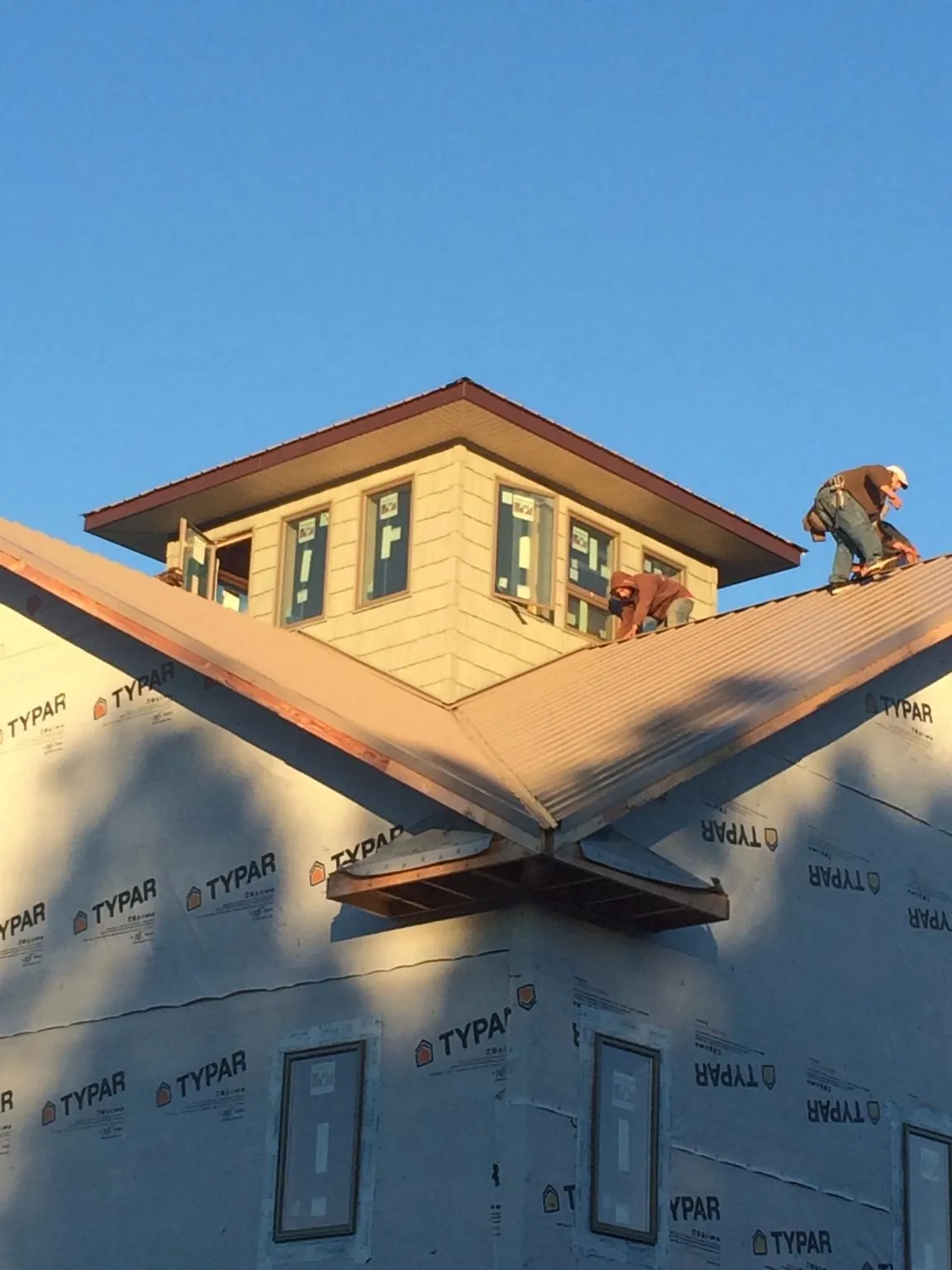 Roofers working around a rooftop cupola on a new metal roof at sunset — Roof Waterproofing in Cataula by Roofing Brothers